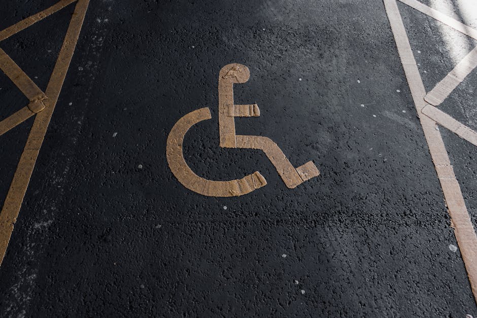 Close-up view of a designated accessible parking space with a wheelchair symbol painted on the asphalt surface in yellow. The space is located outside a property on Townley Road, as indicated in the r