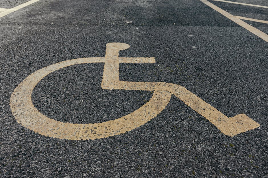 Close-up view of a designated accessible parking space with a wheelchair symbol painted on the asphalt surface in yellow. The space is located outside a property on Townley Road, as indicated in the r